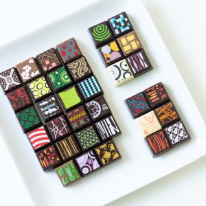 A beautiful dish featuring a wide array of chocolate truffles each decorated with a unique print.